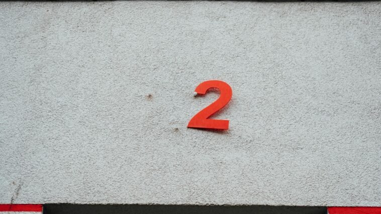 A simple red number 2 on a textured concrete wall with minimalistic design elements.