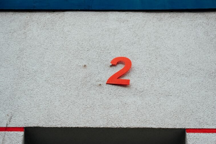 A simple red number 2 on a textured concrete wall with minimalistic design elements.