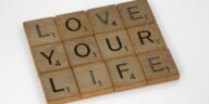 Scrabble tiles arranged to spell 'Love Your Life' against a white background, conveying a positive message.