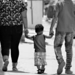 A family of three walks hand-in-hand on a sunny day in Santiago, Dominican Republic.