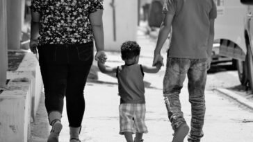 A family of three walks hand-in-hand on a sunny day in Santiago, Dominican Republic.