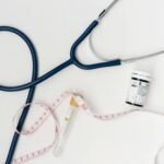 Flat lay of medical tools including stethoscope and measuring tape on a white background.