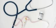 Flat lay of medical tools including stethoscope and measuring tape on a white background.
