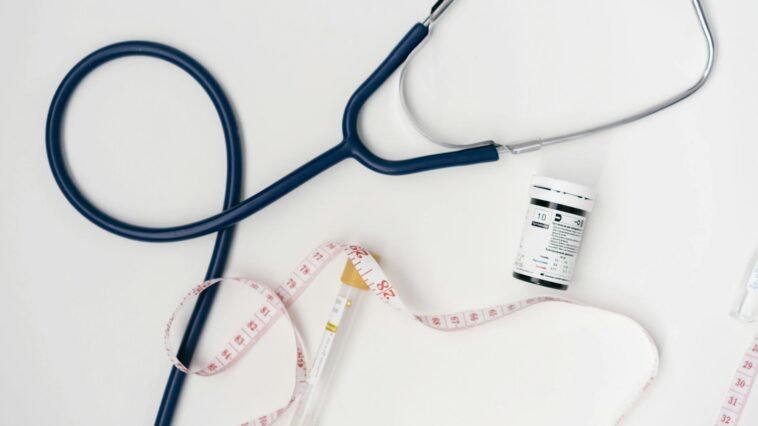 Flat lay of medical tools including stethoscope and measuring tape on a white background.