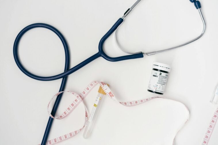 Flat lay of medical tools including stethoscope and measuring tape on a white background.