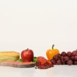 Vibrant display of fruits, vegetables, and salmon on a white background, ideal for food and health themes.