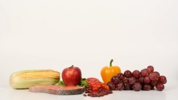 Vibrant display of fruits, vegetables, and salmon on a white background, ideal for food and health themes.