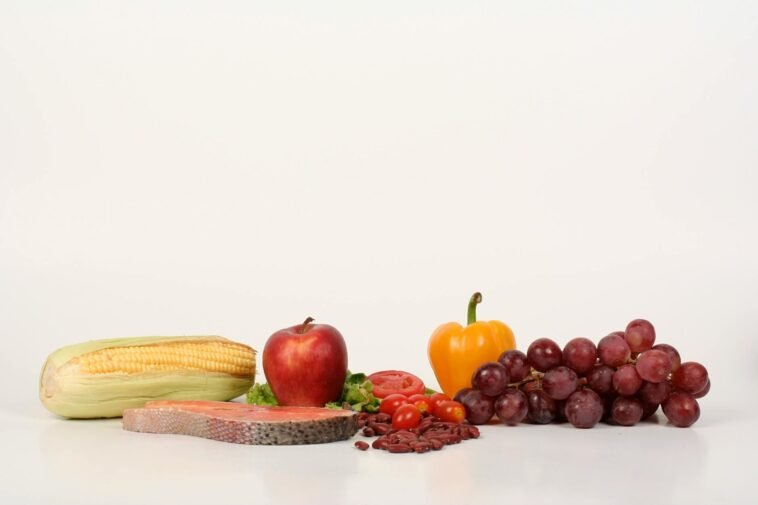 Vibrant display of fruits, vegetables, and salmon on a white background, ideal for food and health themes.