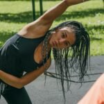 Young woman stretching in a sunny park for a fitness routine, promoting a healthy lifestyle.
