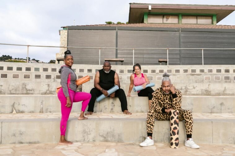 A diverse group of adults dressed in activewear gathered for a yoga session outdoors.