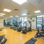 Spacious indoor gym with treadmills, stationary bikes, and exercise equipment on a wooden floor.