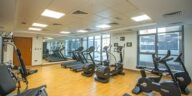 Spacious indoor gym with treadmills, stationary bikes, and exercise equipment on a wooden floor.
