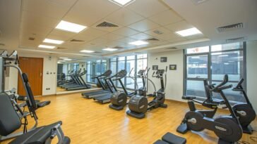 Spacious indoor gym with treadmills, stationary bikes, and exercise equipment on a wooden floor.