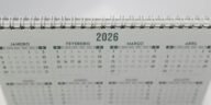 Close-up of a 2026 spiral-bound desk calendar with months in Portuguese.